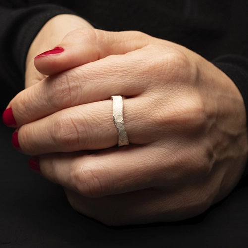 Anillo de plata Crisan Ondu lucido en mano cerrada sobre fondo oscuro