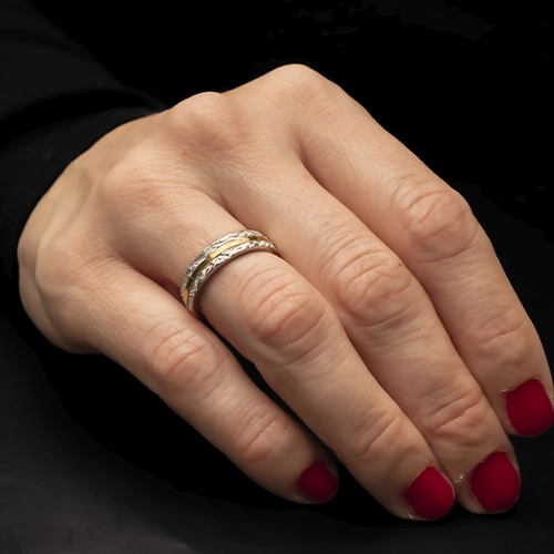 Anillo Tric de plata 925 con textura blanca y línea dorada usado en mano